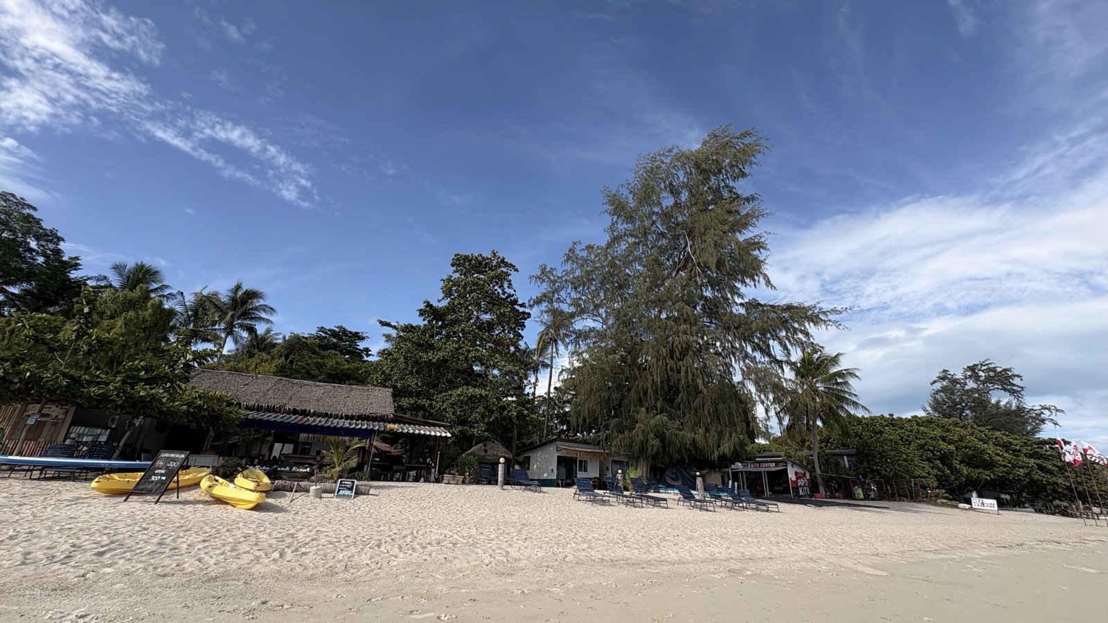 The resort's stretch of beach, with sun loungers and kayaks on the sand.